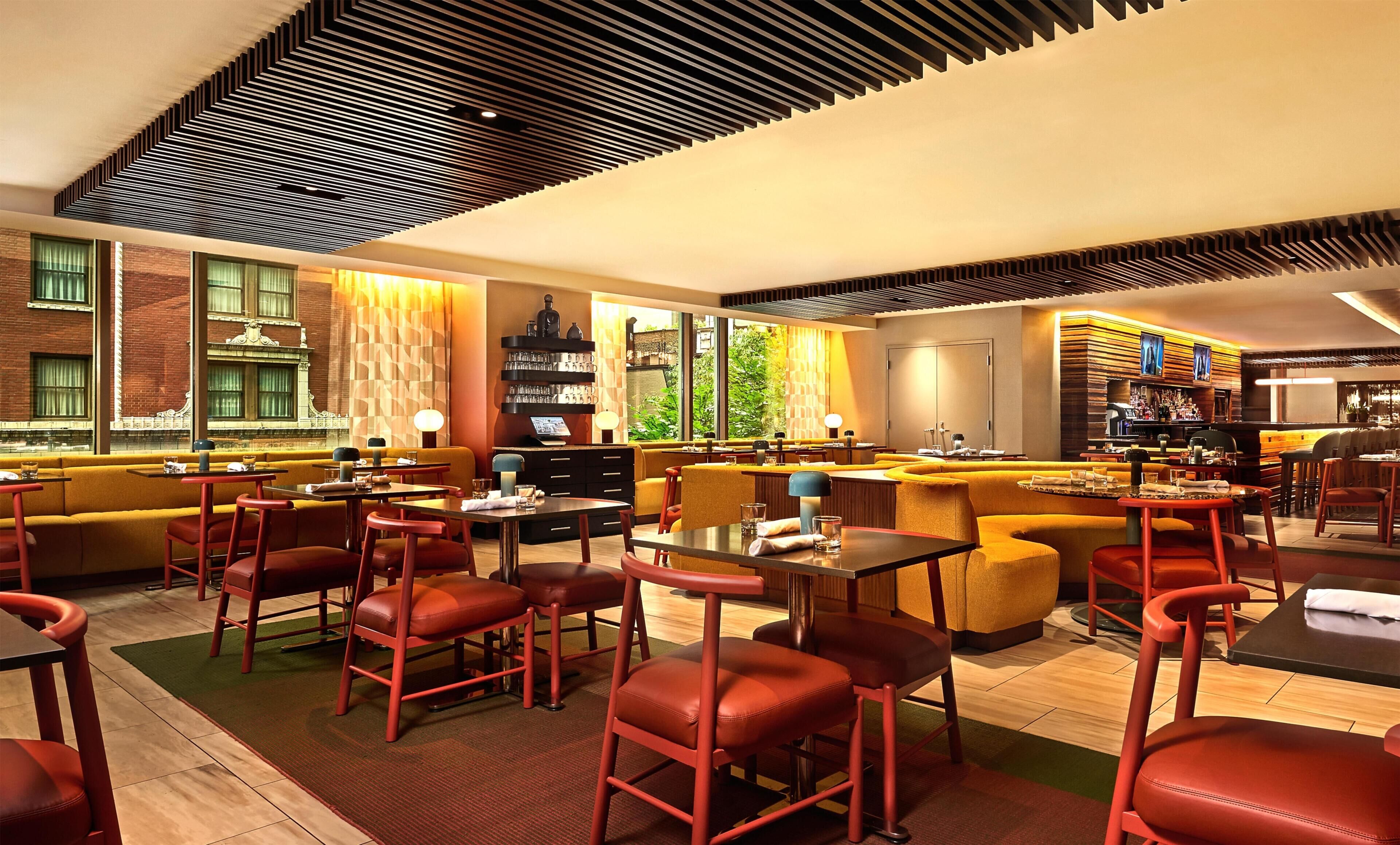 A modern restaurant with high ceilings, exposed brick walls, and a mix of seating options including tables and booths.