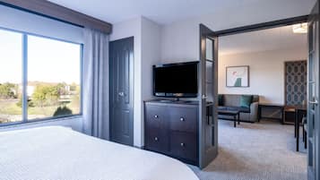 A hotel room with a large bed, a television on a dresser, a sofa, and a view of the outdoors.