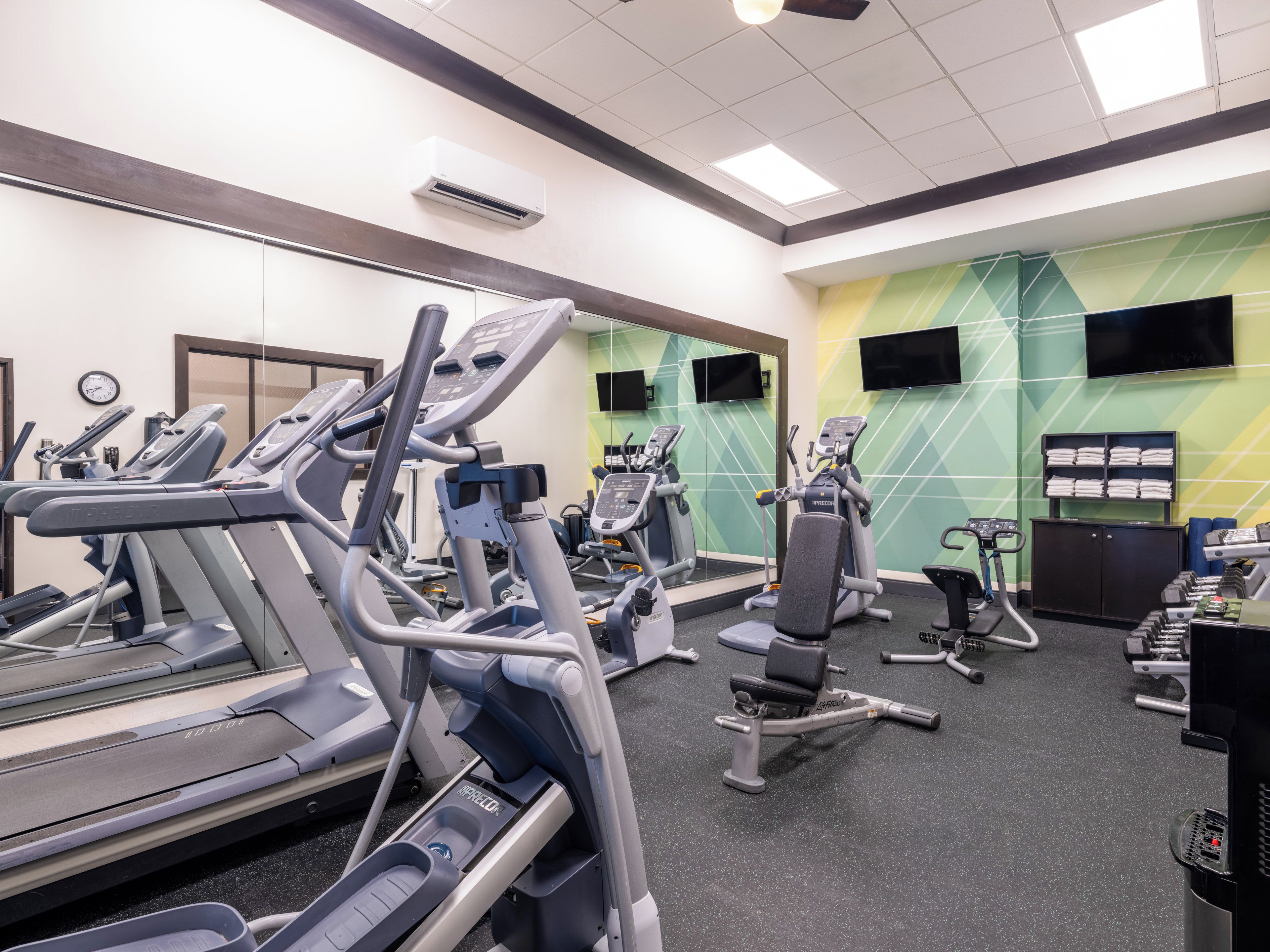A gym with treadmills, elliptical machines, and weight benches.
