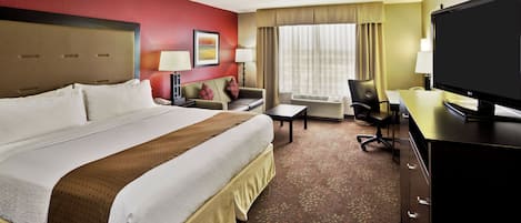 A hotel room with a large bed, a desk, a chair, a television, and a window with curtains.