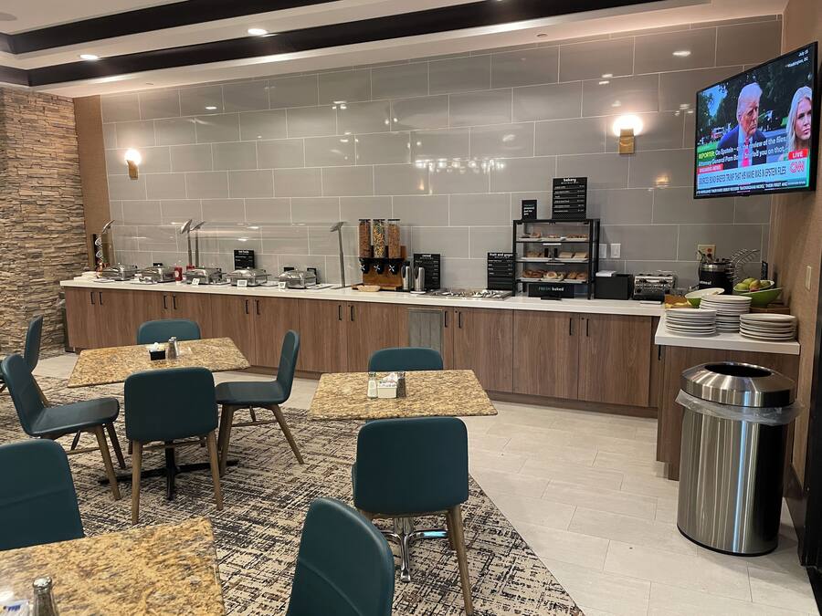Una barra de desayuno moderna con asientos y un televisor que muestra noticias.