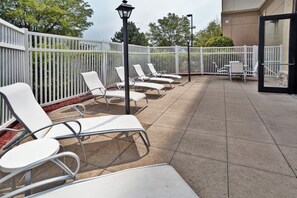 A covered outdoor seating area with white lounge chairs and a white fence. - Holiday Inn Chicago Northwest-Elgin by IHG (Elgin)