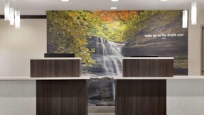 Een receptiebalie met een wanddecoratie van een waterval op de achtergrond en een bord waarop staat: "wake up on the bright side PERU".