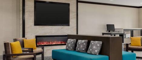 A modern lounge area with a fireplace, seating, and a flat-screen TV.