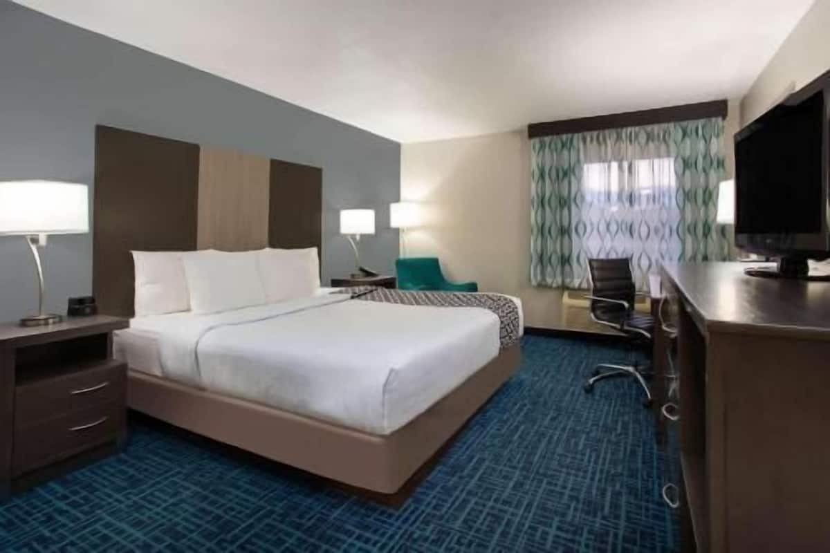 Een hotelkamer met een groot bed, een bureau, een stoel en een televisie.