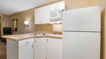 A compact kitchen with white cabinets, a microwave, and a refrigerator.