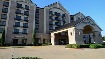 A multi-story hotel with a prominent entrance and a clear sky.