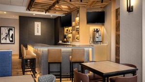 Een moderne bar met een toog, zitplaatsen en een televisie.