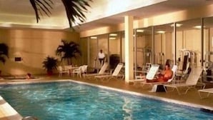 A swimming pool with lounge chairs and a person swimming.
