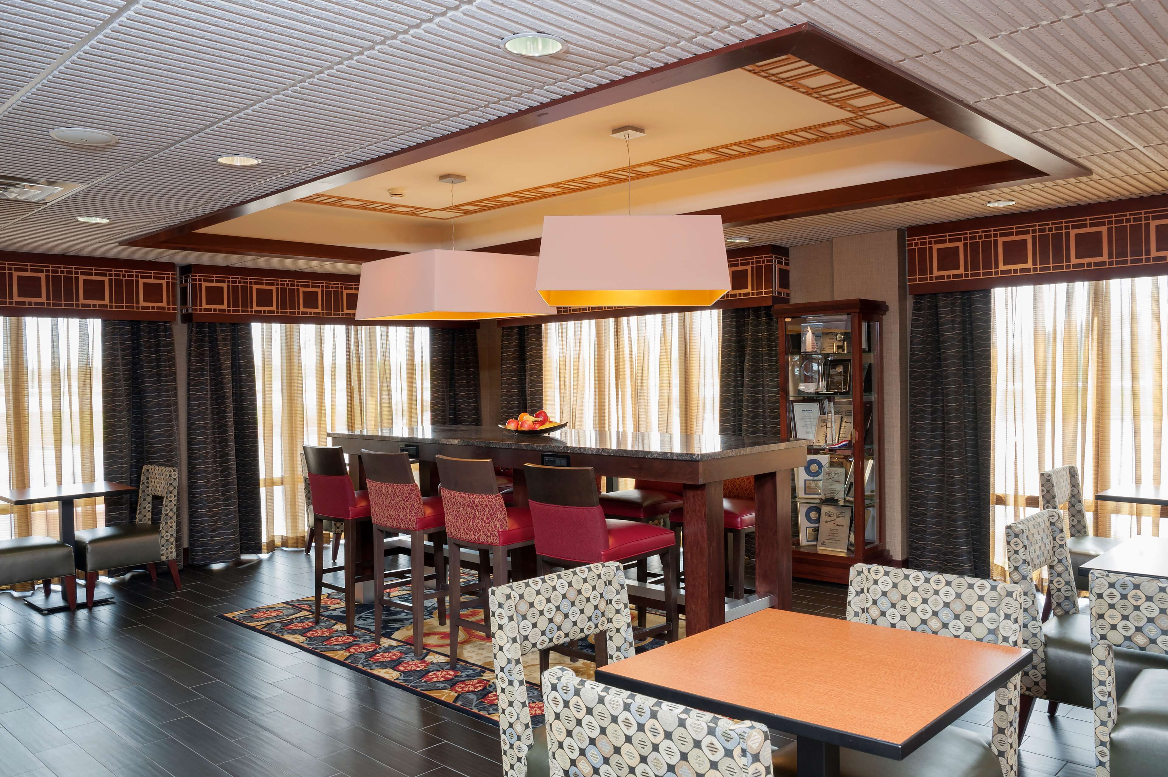 A dining area with a central table, red chairs, patterned chairs, and a decorative ceiling.
