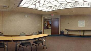 A conference room with a long table and chairs, a ceiling with a geometric pattern, and an exit sign.