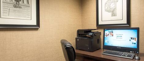 A desk with a printer, a laptop, and framed artwork on the wall.