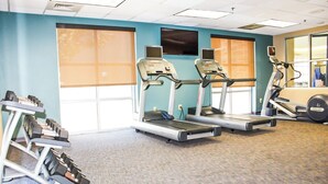 Sala de ginástica com esteiras, bicicleta ergométrica e banco de musculação.