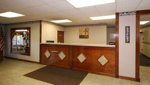 A reception area with a wooden reception desk, a large American flag, and a framed artwork on the wall. - Beaver Dam Inn (Beaver Dam)