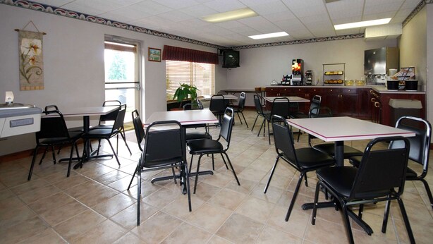 A restaurant with multiple tables and chairs, a coffee machine, and a television on the wall. - Beaver Dam Inn (Beaver Dam)