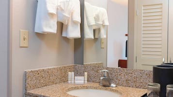 A bathroom with a granite countertop sink, a mirror, and two white towels hanging on a towel rack.