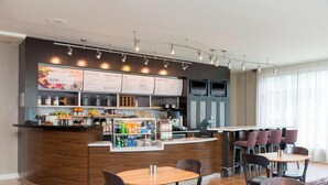 A modern bistro with a wooden counter, menu boards, and seating area with tables and chairs. - Courtyard by Marriott Louisville Downtown (Louisville)