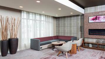 Una sala de estar moderna con un sofá modular, una mesa de centro redonda y dos sillones. Hay un televisor de pantalla plana montado en la pared y una pieza decorativa encima.