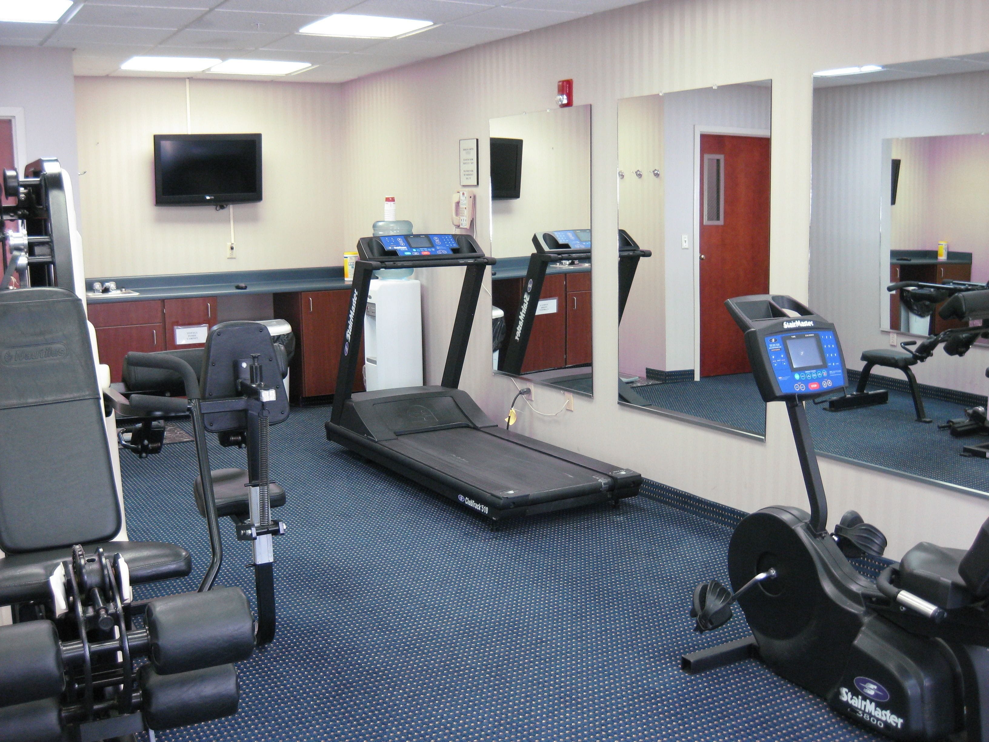 A gym with treadmills, exercise bikes, and a water dispenser.