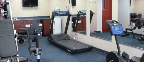 A gym with treadmills, exercise bikes, and a water dispenser.