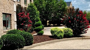 A building with a brick facade, surrounded by well-maintained landscaping including various shrubs and flowering plants. - Ramada Limited Mount Sterling (Mount Sterling)