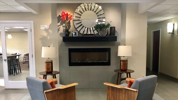 A lobby with two armchairs, a fireplace, and a large mirror. - Ramada Limited Mount Sterling (Mount Sterling)
