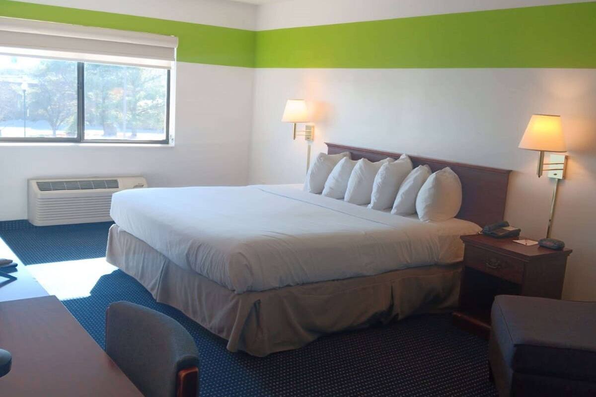 A hotel room with a large bed, two bedside lamps, a desk, and a chair.