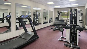 A gym with treadmills, a weight machine, and mirrors on the walls. - Ramada Limited Mount Sterling (Mount Sterling)