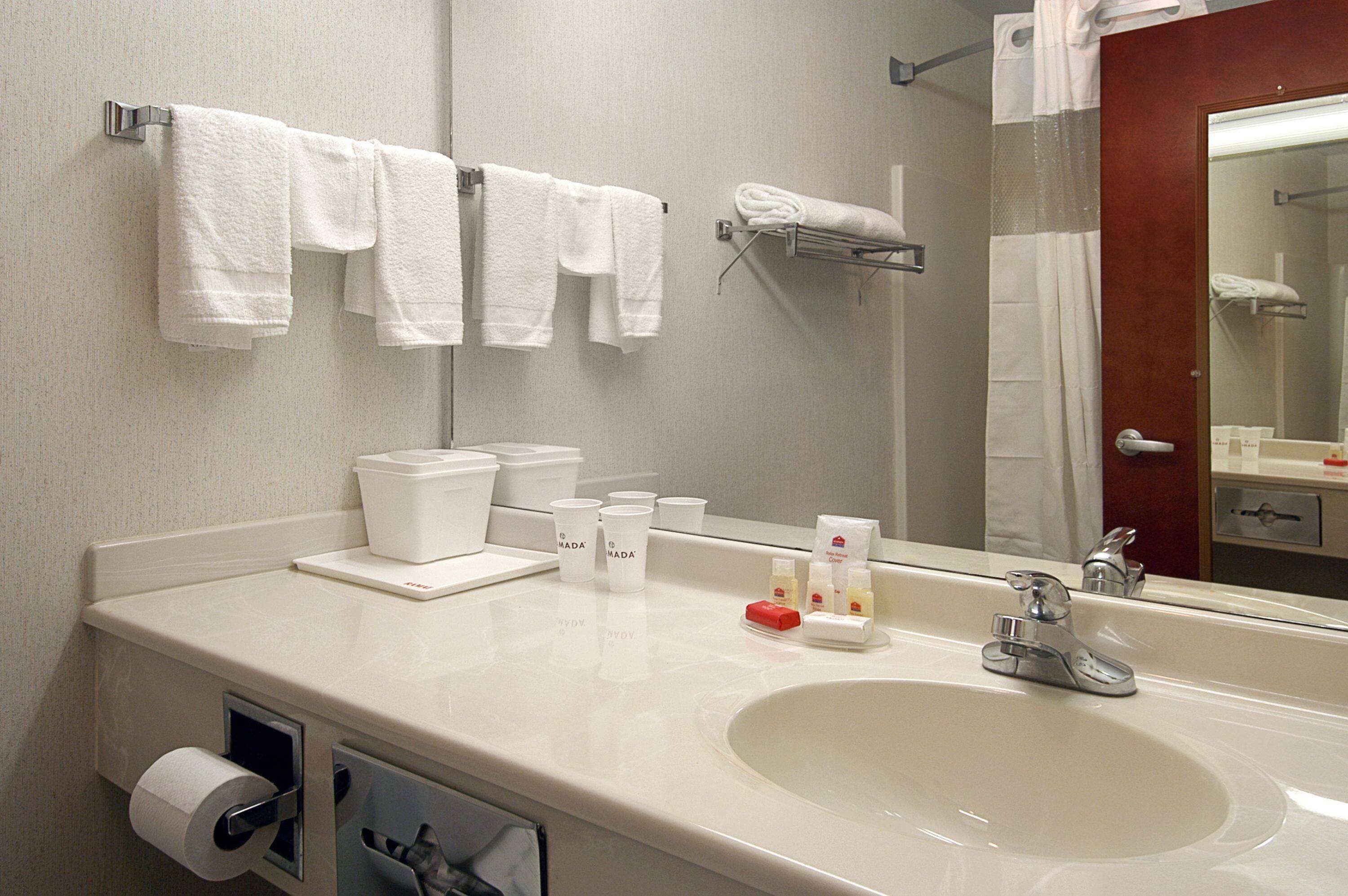Ein Hotelbad mit Waschbecken, Spiegel, Handtuchhalter und Pflegeprodukten.
