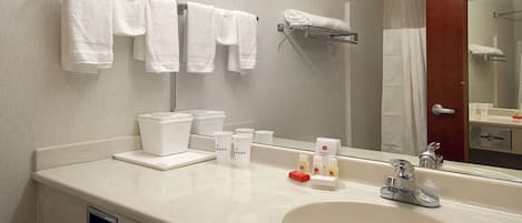 Ein Hotelbad mit Waschbecken, Spiegel, Handtuchhalter und Pflegeprodukten.