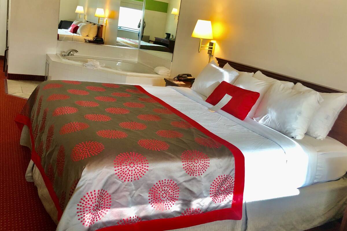 A hotel room with a bed, a bathroom, and a large mirror.