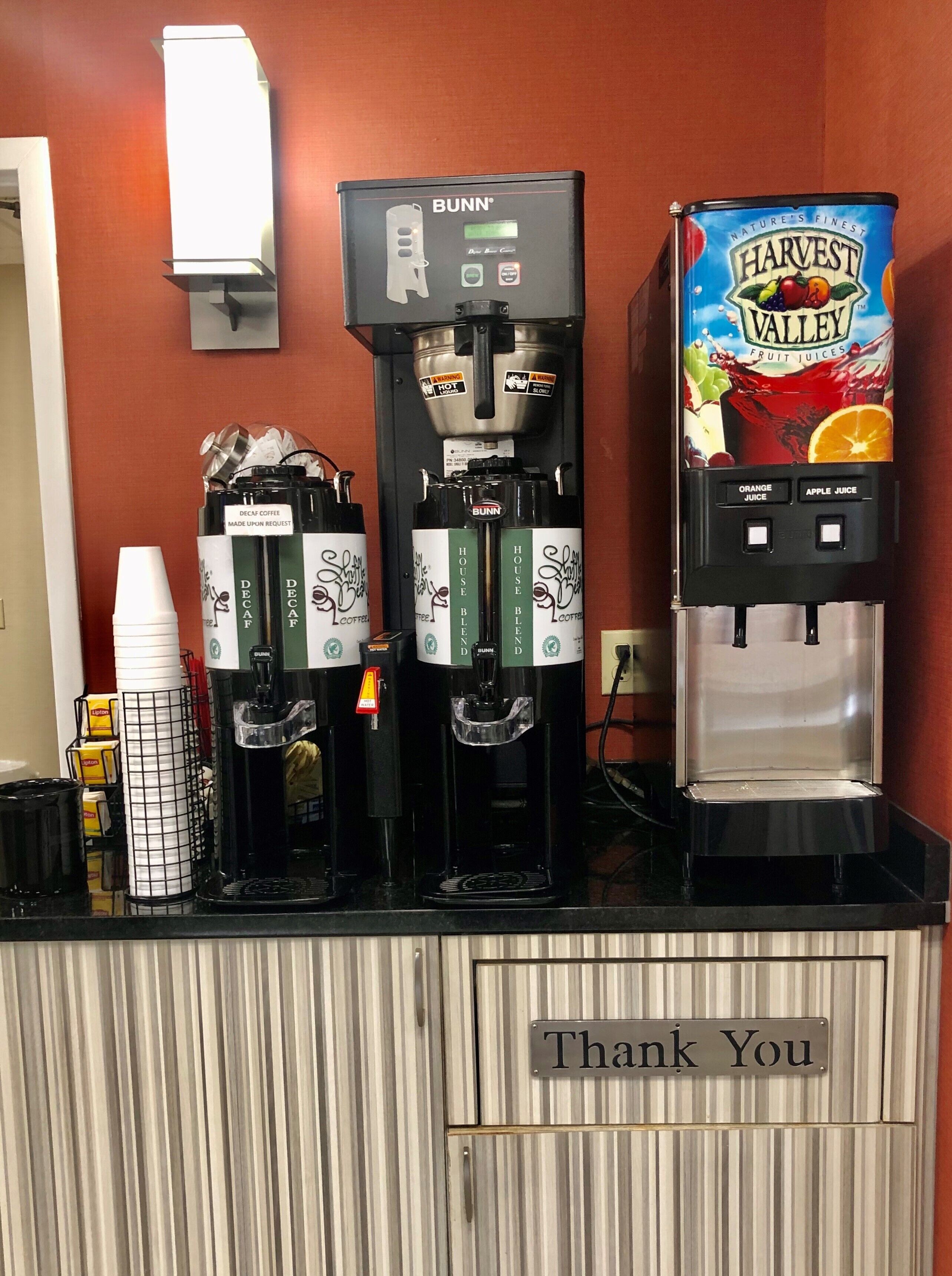 Eine Kaffeestation mit entkoffeiniertem Kaffee und der Kaffee-Mischung des Hauses, ein Warmwassergerät und ein Fruchtsaftspender.