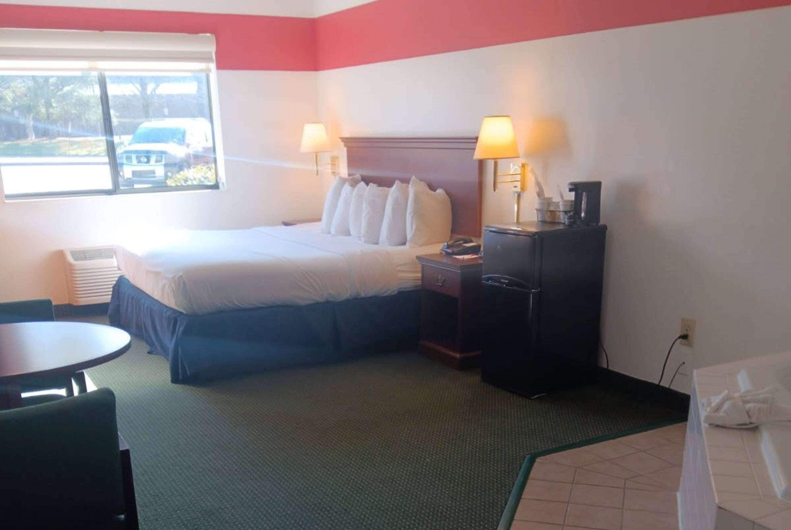 A hotel room with a bed, two bedside tables with lamps, a desk, and a chair.