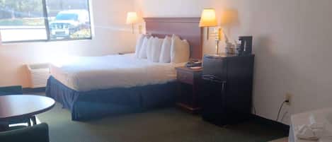 A hotel room with a bed, two bedside tables with lamps, a desk, and a chair.