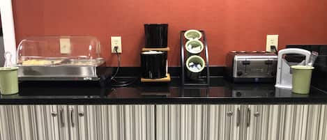 A kitchenette with a toaster, a coffee maker, and a food warmer.