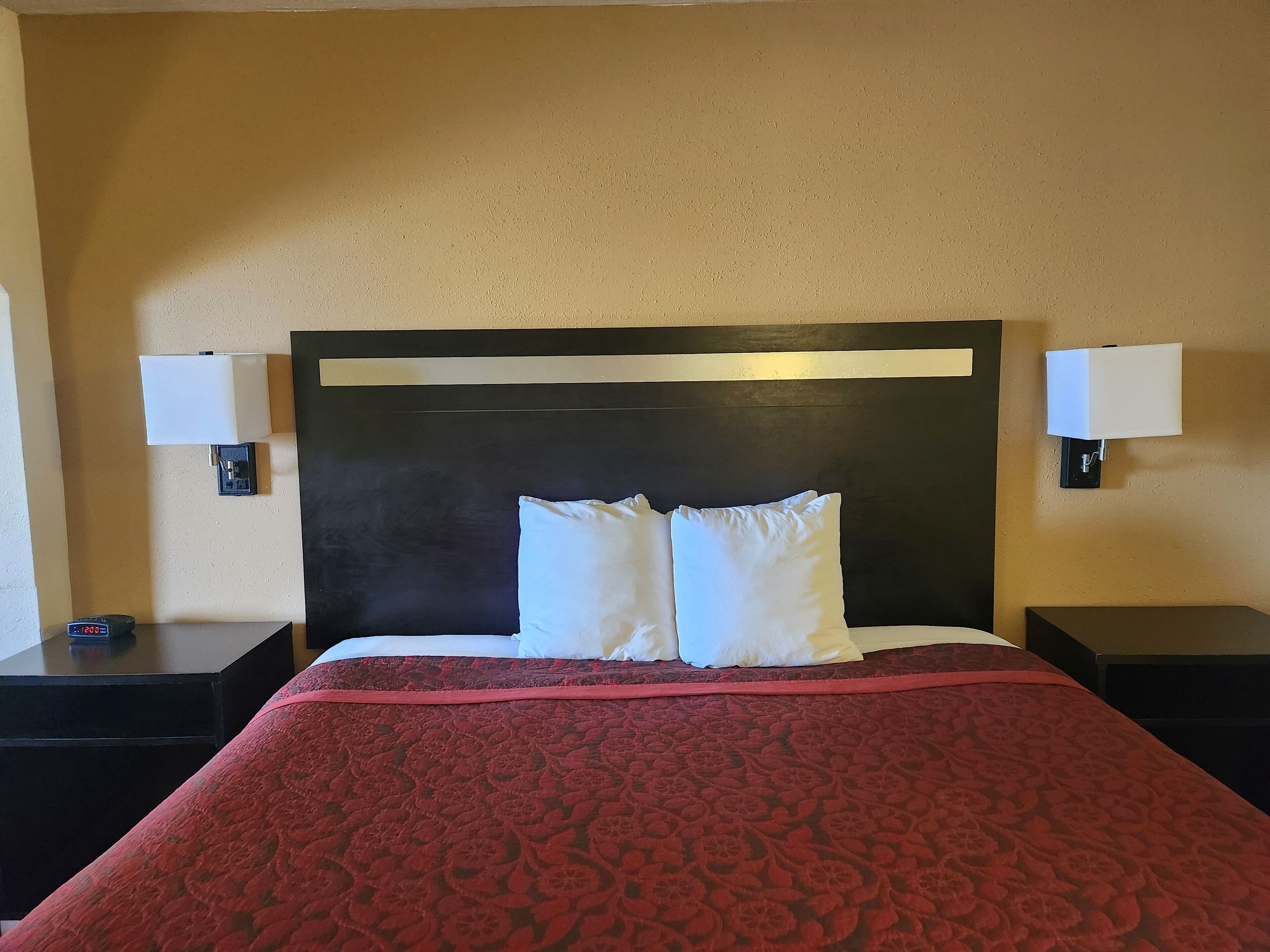 Una habitación de hotel con una cama grande, dos mesitas de noche y dos lámparas de pared.