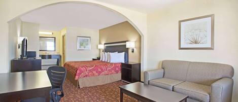 A hotel room with a bed, a sofa, a desk, and a chair.