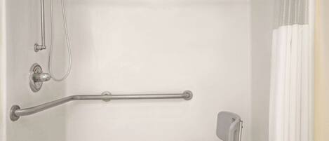 Une salle de bain équipée d’une douche, de barres d’appui et d’un marchepied.