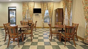 A dining area with checkered flooring, wooden tables, and striped cushioned chairs. - Days Inn by Wyndham Hammond (Hammond)