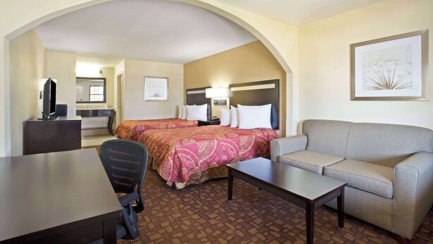 A hotel room with a bed, a sofa, a desk, and a chair. - Days Inn by Wyndham Hammond (Hammond)