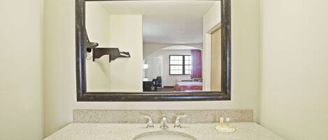 Une salle de bain avec un comptoir en granit, un lavabo et un miroir.