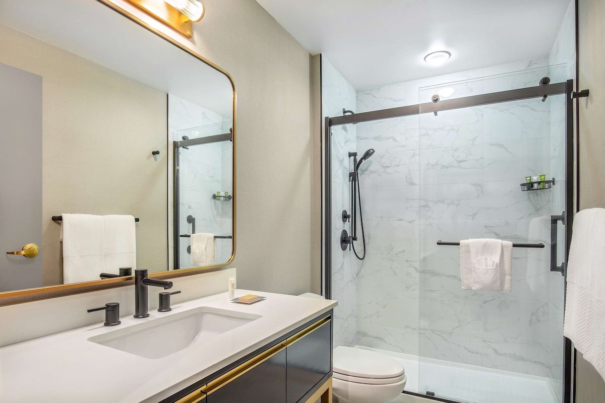 A modern bathroom with a glass-enclosed shower, a large mirror, and a white sink.