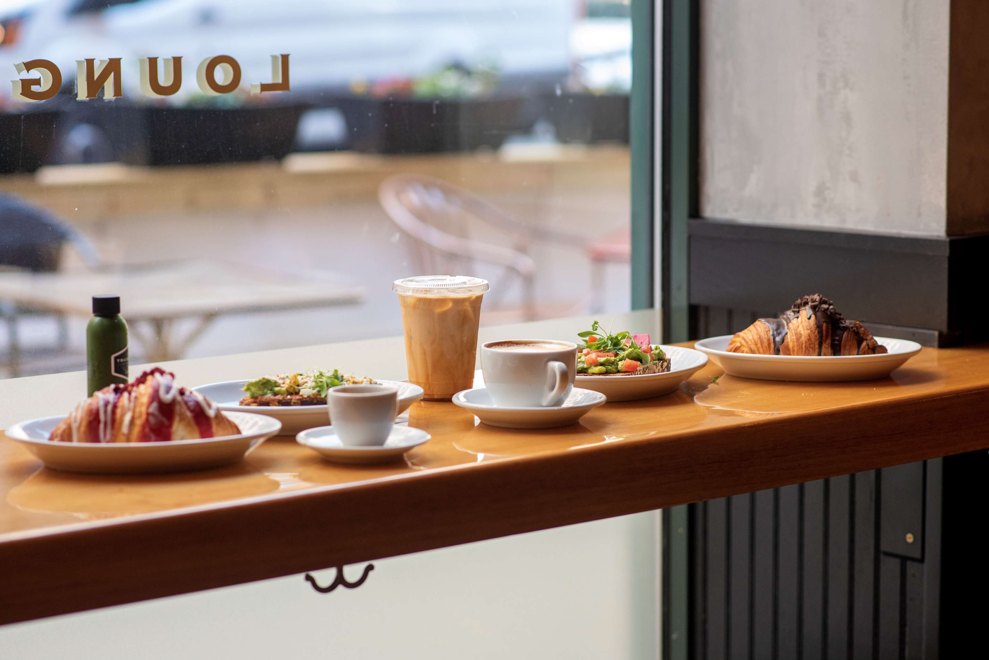 Un comptoir de café proposant une variété de produits alimentaires et de boissons, notamment des pâtisseries, un croissant, du café et une salade.