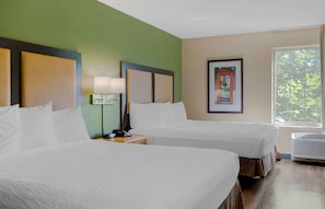 A hotel room with two beds, a nightstand with a lamp, a framed picture on the wall, and a window with a view of trees. - Extended Stay America Suites Boston Waltham 52 4th Ave (Waltham)
