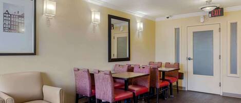 A hotel dining area with a sofa, tables, and chairs.