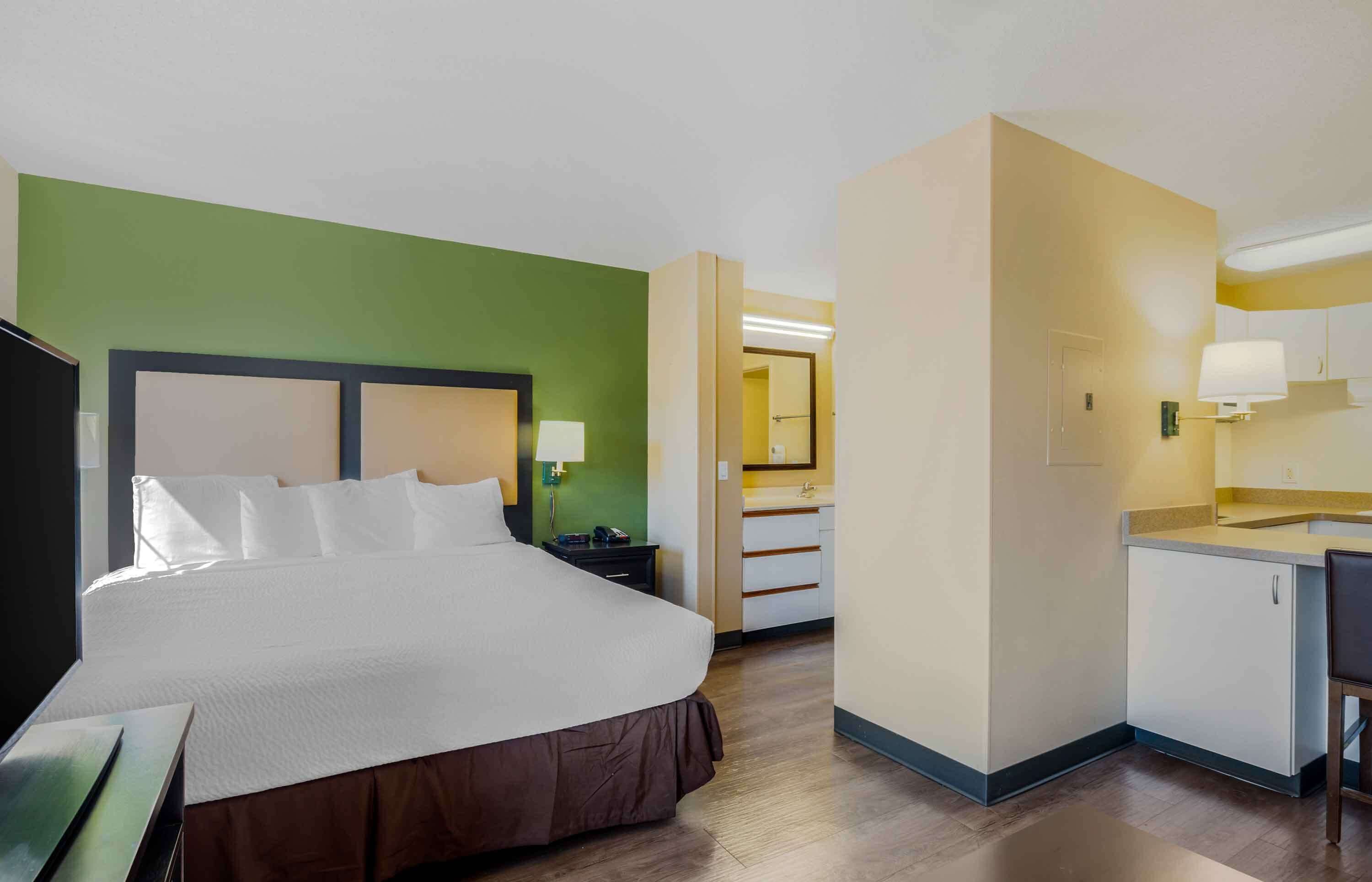 Una habitación de hotel con una cama grande, un escritorio y una kitchenette.