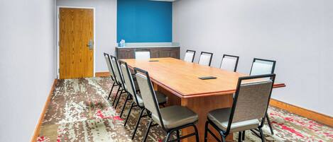 Una sala de conferències amb una taula llarga, sis cadires, una paret d'accent blava i una catifes amb disseny.