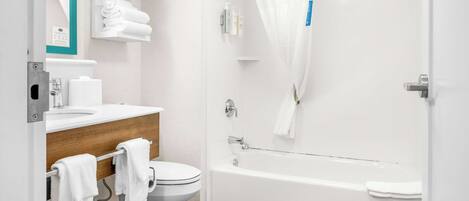 A modern bathroom with a toilet, sink, and bathtub.