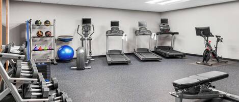 A gym with treadmills, elliptical machines, a stationary bike, and weightlifting equipment.
