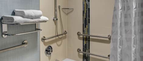 A modern bathroom with a bathtub, grab bars, and a towel rack.
